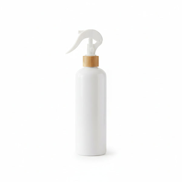 White spray bottle with wooden cap on a light surface with plants in the background